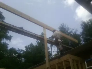 Carpenter setting a ridge beam over a new addition frame — Ice Dam Removal by Roofing Brothers in Wever