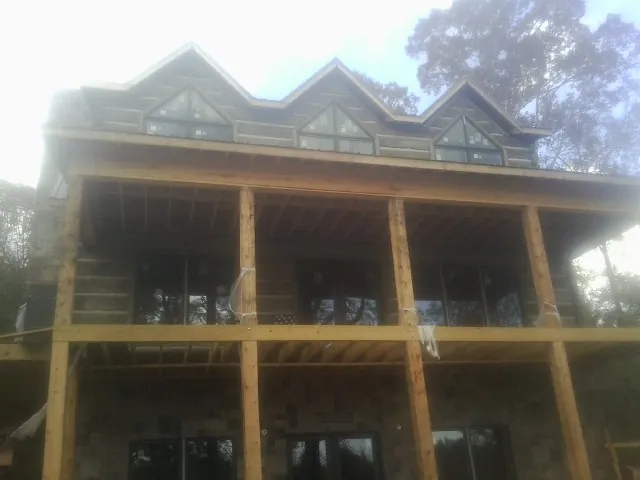 Dormers and porch framing on a large log home under construction — Roof Coating work by our crew in Wever