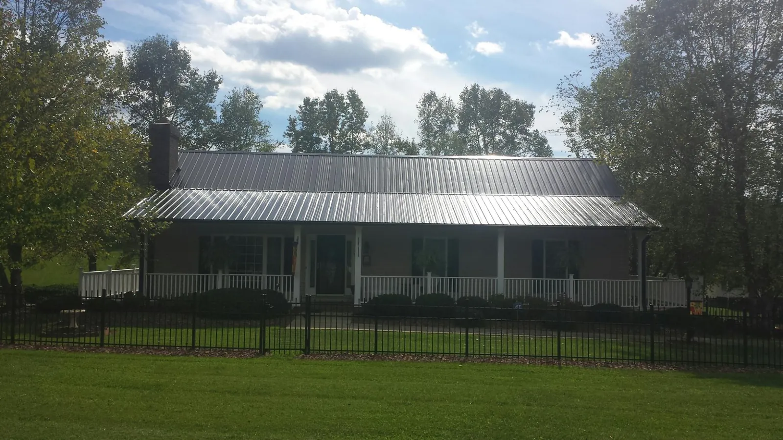 Gray metal roof on a brick ranch with a full width front porch — Gutter Guard Installation work by our crew in Wever