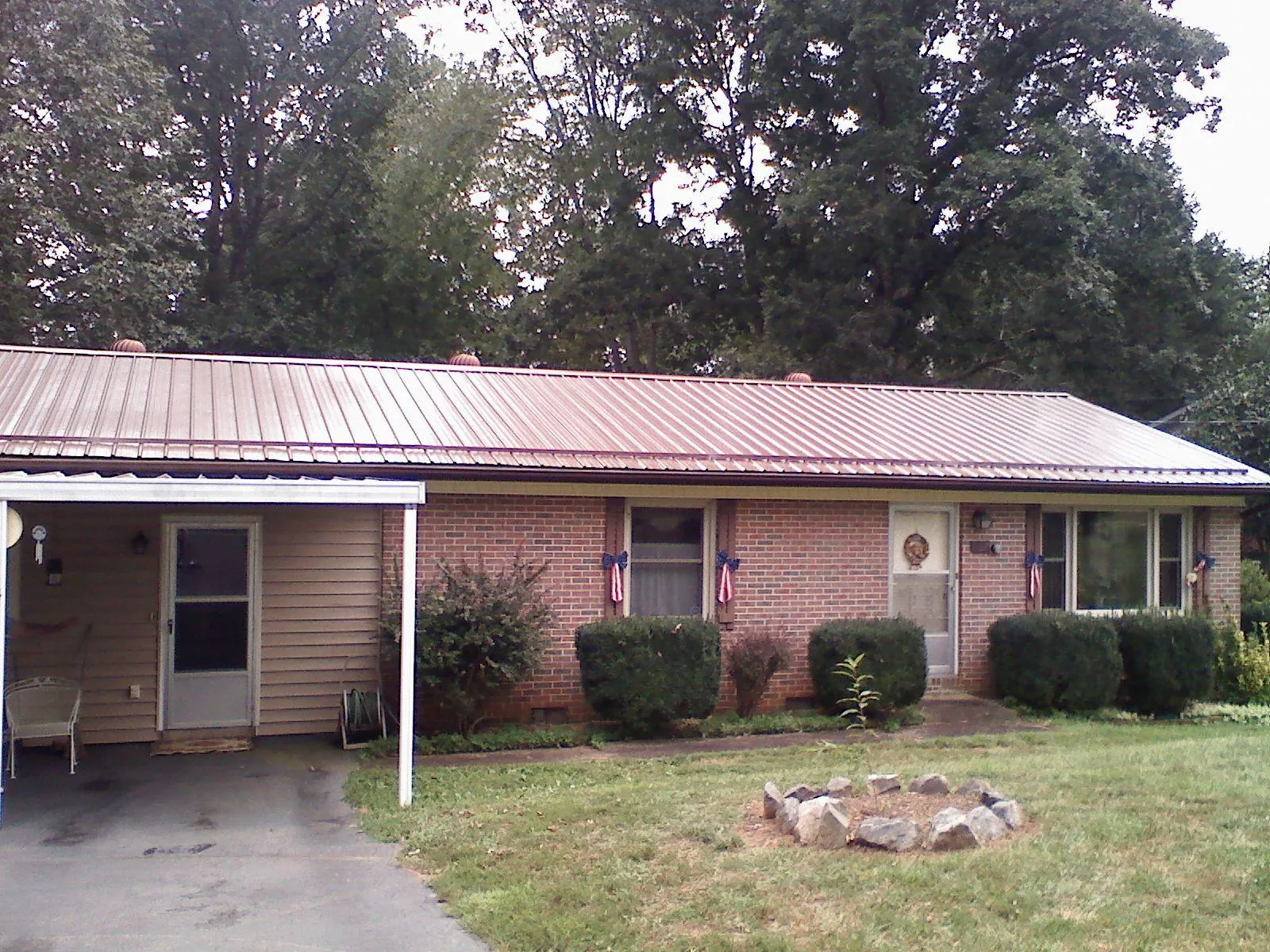 Bronze metal roof and carport on a brick ranch home — Roof Repair work by our crew in Wever